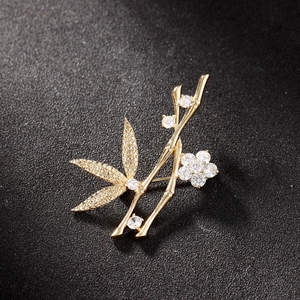 Broche bambou en or avec zircons blancs brillants sur fond de texture noire