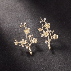 Macro-opname van vergulde bloemtak broche met ingelegde zirkonia kristallen steentjes