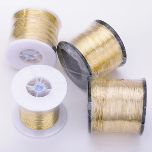 Four spools of golden jewelry wire for DIY crafts on black and white plastic bobbins