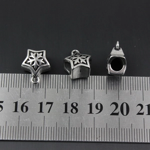 Dettaglio di un ciondolo a stella vintage accanto a un righello che mostra la misura 12mm