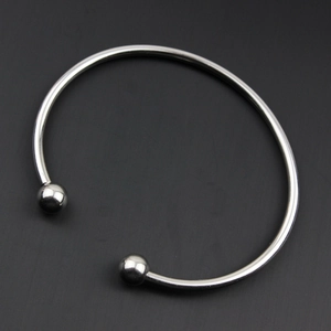 Dettaglio del bracciale rigido aperto in acciaio inossidabile lucido con estremità a sfera