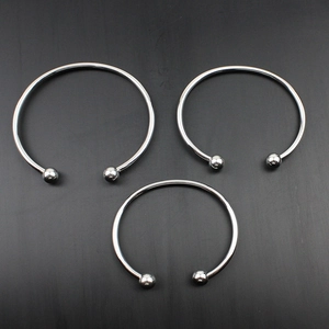 Set di tre bracciali rigidi in acciaio inossidabile argento con terminali a sfera su grigio