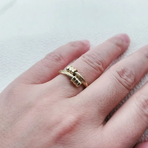 Gros plan d'une bague torsadée en acier inoxydable plaqué or 18 carats au doigt