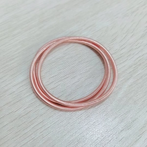 Bracelets à ressort en spirale triple épaisseur or rose sur fond bois clair