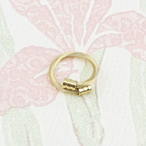 Détail d'une bague en acier inoxydable plaqué or 18K avec design torsadé et embouts