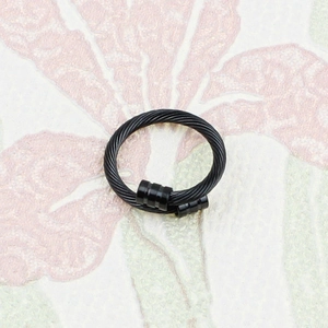 Détail d'une bague ouverte noire en câble d'acier inoxydable avec embouts cylindriques