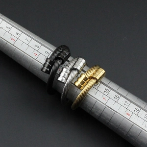 Gros plan de bagues en câble d'acier torsadé noir, argent et or sur un baguier de mesure