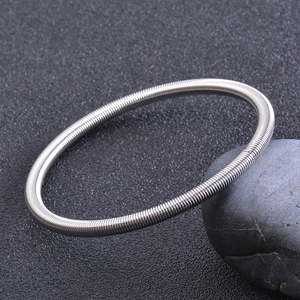 Makro-Detail des silbernen Gitarrensaiten-Armbands mit Spiraltextur aus Federstahl