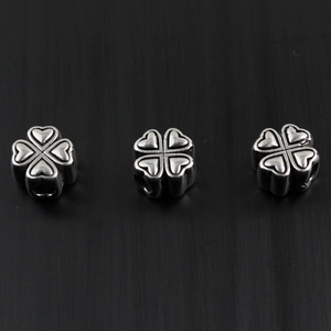Macro view of three vintage silver heart clover beads with engraved cross details