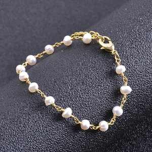 Detail of gold chain bracelet with white pearls and lobster clasp on black background