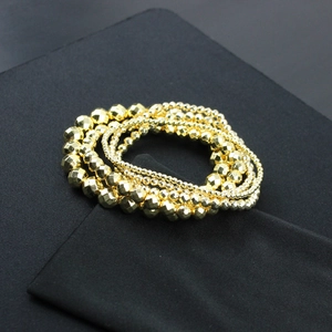 Macro shot of gold-plated faceted beads with shimmering metallic luster on black fabric