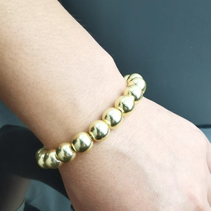 Vista macro del bracciale elastico con perline placcate oro 14K e finitura lucida a specchio
