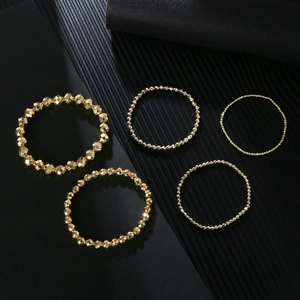 Detail view of five-piece 14K gold plated faceted bead elastic bracelet set on black background