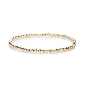 Detail of faceted gold beads on a minimalist stretch bracelet with metallic texture