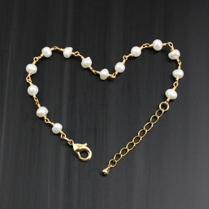 Detail of a gold chain bracelet with freshwater pearls arranged in a heart shape
