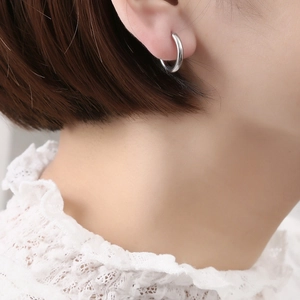 Boucles d'oreilles créoles minimalistes en acier inoxydable argenté portées par un mannequin