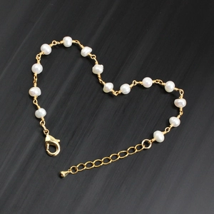 Macro detail of handmade freshwater pearl chain bracelet with gold wire wrap and heart shape