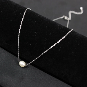 Detailed macro view of a natural freshwater pearl pendant on a fine silver link chain
