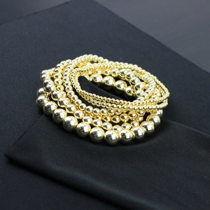 Dettaglio di bracciali con perline placcati oro 14K con superficie lucida su fondo nero