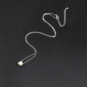 Macro detail of minimalist stainless steel necklace featuring a lustrous freshwater pearl