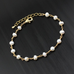 Detail view of freshwater pearls on a gold chain bracelet with lobster clasp and extender