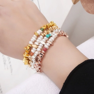Détail de cinq bracelets superposés avec perles d'eau douce et perles métalliques