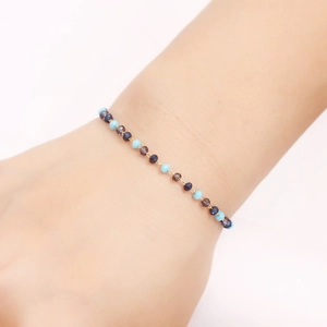 Handmade gold beaded bracelet with blue faceted crystal beads shown on a female wrist