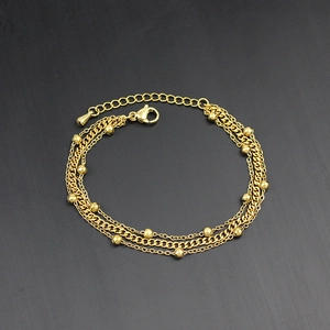 Detailed view of triple-layered gold bead chain bracelet with lobster clasp and texture