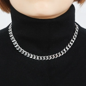 Détail de collier chaîne gourmette argentée sur col roulé montrant un éclat métallique