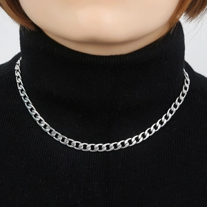 Close-up of a thick silver Cuban curb chain necklace on a black turtleneck sweater