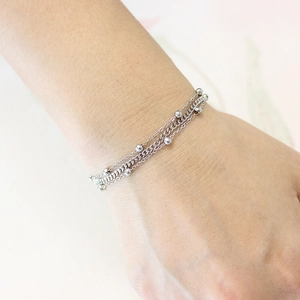 Detailed close-up of triple-layer stainless steel bead chain bracelet on female wrist