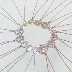 Macro view of multi-layered coin necklaces with Elizabeth II relief in gold, silver, and rose gold