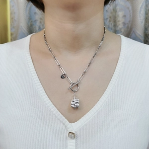 Collana a graffetta argento con chiusura OT e ciondolo a cuore su una donna