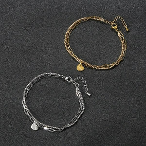 Dettaglio di bracciali in acciaio oro 18k e argento con perline e ciondoli a cuore
