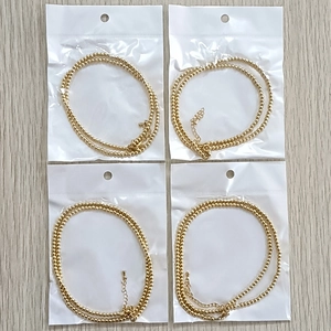 Dettaglio di quattro collane con sfere dorate da 3 mm in confezione con chiusura