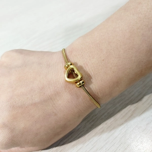 Dettaglio di un bracciale a catena a serpente dorata con ciondolo a forma di cuore