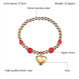 Détail d'un bracelet perles en acier inoxydable doré PVD avec agate rouge et pendentif cœur