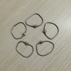 Dettaglio di cinque braccialetti a catena serpente in acciaio inox argento su legno