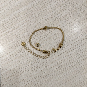 Dettaglio del bracciale a catena serpente dorata con chiusura a moschettone e pendente cuore