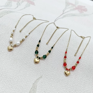 Vue détaillée des colliers à pendentif cœur avec perles blanches, vertes et rouges sur doré