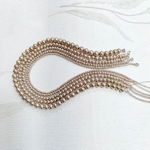 Detailed macro view of rose gold beaded necklaces with smooth polished mirror finish surface