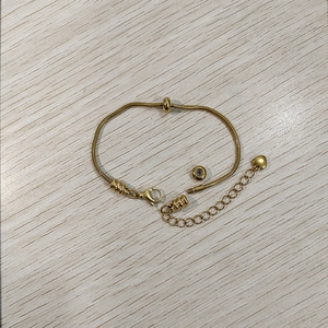 Dettaglio del bracciale a serpente dorato con chiusura a moschettone e cuore