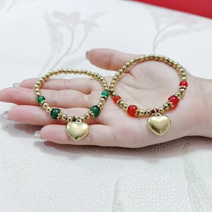 Détail de colliers perlés dorés avec pendentifs cœurs et perles d'agate vertes et rouges