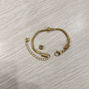 Dettaglio del bracciale a catena serpente dorata con ciondolo a cuore e chiusura a moschettone