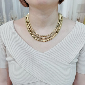 Detail of a triple-layered gold bead necklace showcasing polished finish and layered style