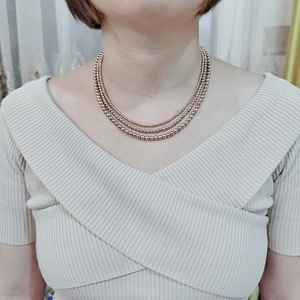 Three-layer rose gold stainless steel bead necklace shown on model neck closeup