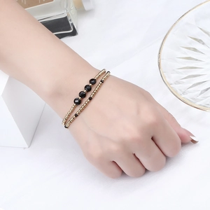 Close-up of double-layer gold beaded bracelet with black faceted crystals on wrist