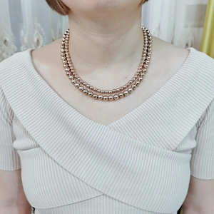 Detail of double-layer rose gold stainless steel bead necklace worn by a model