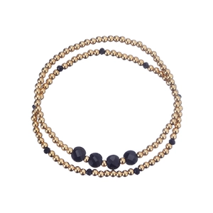 Detail of double-layer stretch bracelet with gold beads and black faceted crystals