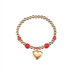Détail d'un bracelet de perles dorées avec touches rouges et grand pendentif en cœur